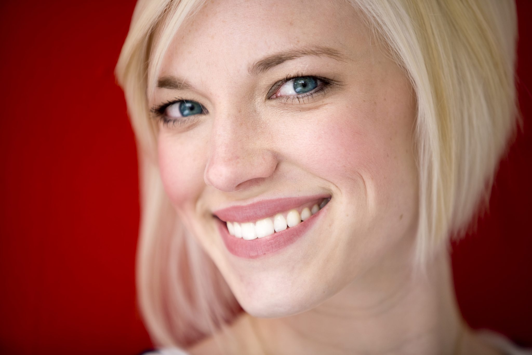 Blonde woman against red background after minor tooth extractions.
