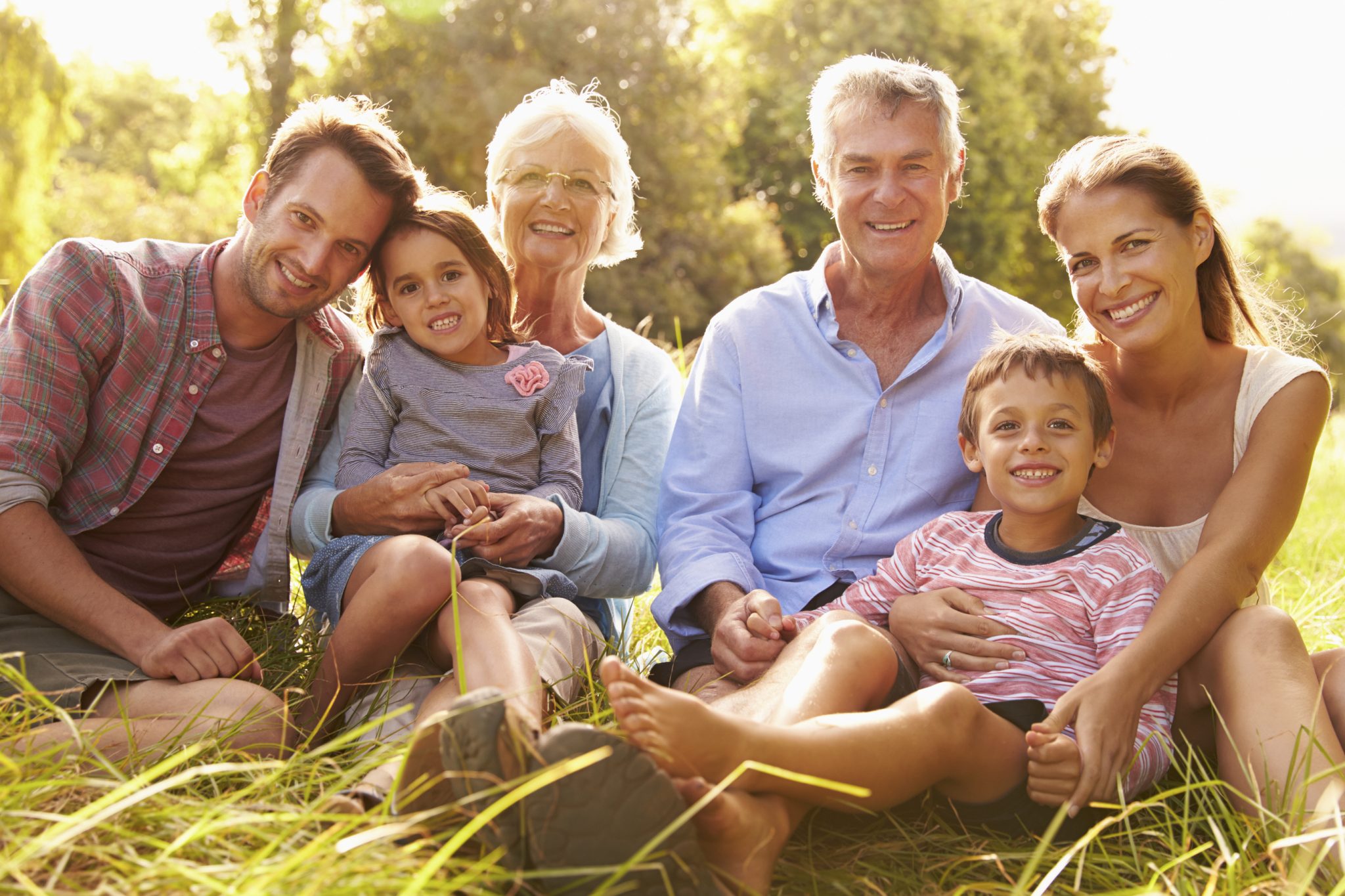 Multi-generation family relaxing together outdoors, smiling to camera