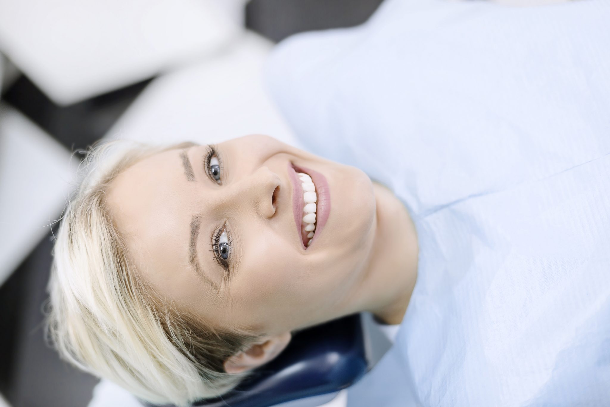Woman smiling while getting her teeth professionally whitened by her dentist.
